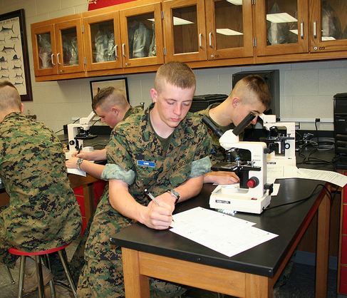 A military school student in biology class takes notes.