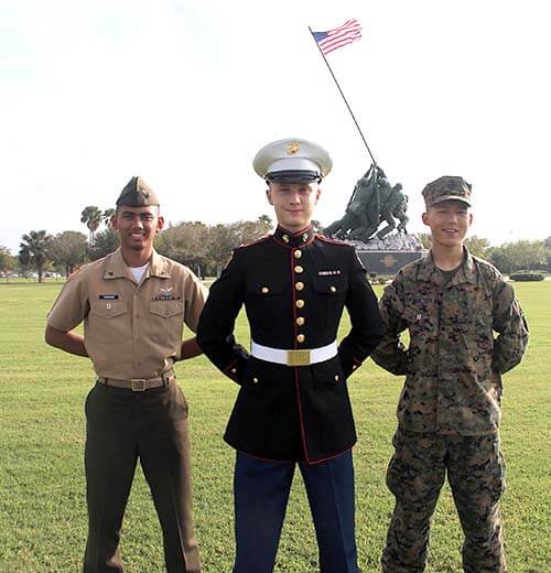 Three military school cadets in three different MJROTC uniforms.